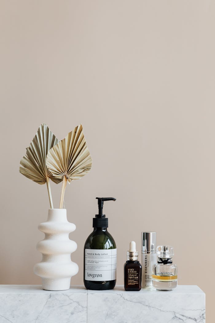 hero-img-01 Minimalist bathroom shelf featuring skincare bottles and decorative beige vase.
